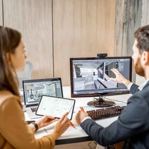 An architectural team reviewing 3D building designs on multiple screens, collaborating digitally to improve efficiency through ongoing IT support.