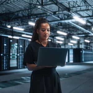 An IT technician in a network facility holding a computer