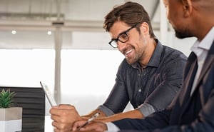 2 people in a conference meeting reviewing information on a tablet